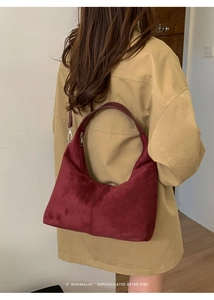 Detail showing the matte burgundy suede texture and minimalist half-moon shape of the bag
