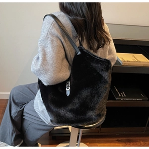 Détail d'un sac cabas en peluche noire avec lanières en cuir et fermoir rotatif argenté