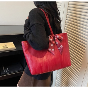 Detail of red tote bag with wavy texture and silk ribbon featuring Xi character