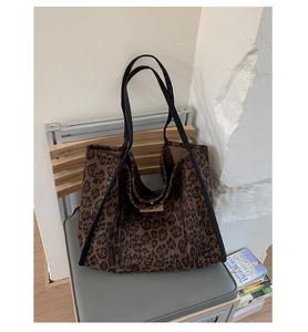 Detailed view of leopard print tote bag with black straps on a gray seat setting