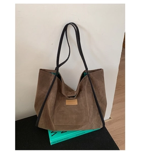 Detail view of large brown suede tote bag featuring a Hopeful label and green plaid lining