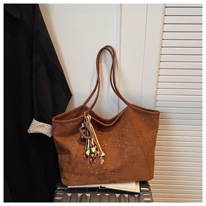 Detail view of brown suede tote bag with golden rivets and ethnic style keychain