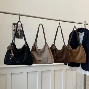 Detail of four suede tote bags with heart charms and tassels in earthy tones
