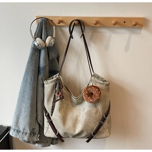 Detail of vintage beige tote bag hanging on wooden hook with plush donut charm