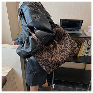 Detailed view of leopard print tote bag with wide strap on shoulder in office setting