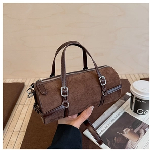 Macro detail of dark brown suede Boston bag with smooth leather strap and metal buckles