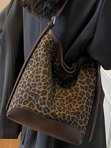 Leopard print hobo bag with brown leather straps styled on a gray blazer