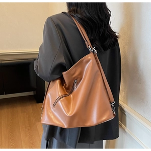 Detail view of a brown vintage tote backpack showing soft leather texture and metal zipper