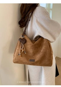 Close-up of brown suede tote bag with heart charm and decorative beaded tassels