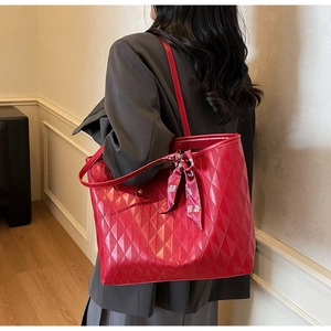 Detail of red quilted tote bag with silk scarf accessory worn over a grey blazer jacket