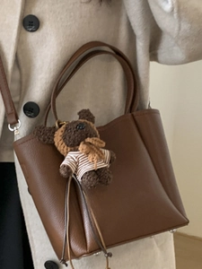 Brown leather tote bag with a cute teddy bear pendant and long shoulder strap