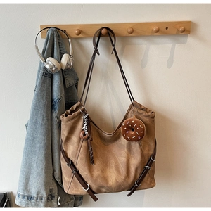 Detail of vintage brown tote bag with chocolate donut plush charm and stylish silver hardware