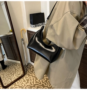 Polished black semi-moon underarm bag styled with minimalist lifestyle aesthetic