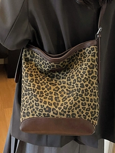 Minimalist leopard print canvas bucket bag with brown leather trim worn by model