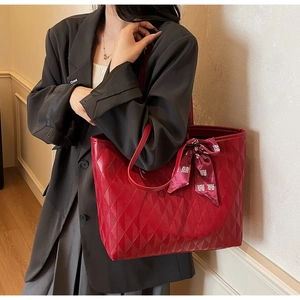 Detail of red quilted tote bag featuring a decorative wedding silk scarf on the handle