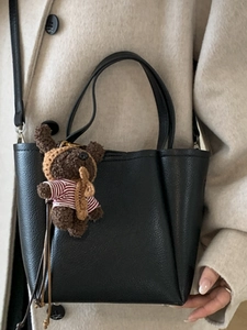 Minimalist black pebble leather bucket bag with a cute bear charm for daily travel use