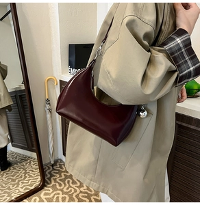 Détail du sac demi-lune bordeaux brillant avec fermetures éclair en métal argenté
