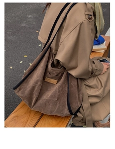 Detail of a large brown suede tote bag with HOPEFUL leather patch in an autumn setting