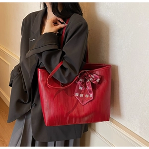 Red tote bag with ribbon bow and Chinese Xi character detail worn by model