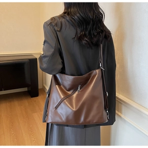 Rear view of a large brown leather tote bag showing size and drape on a model's shoulder