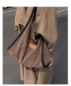 Detail of a large brown suede tote bag featuring a HOPEFUL logo and black woven straps