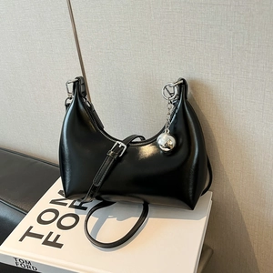 Détail du sac d'épaule noir brillant avec pendentif sphère argenté et design chic