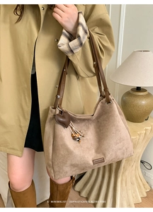 Close-up of matte suede tote bag featuring heart pendant and leather shoulder strap