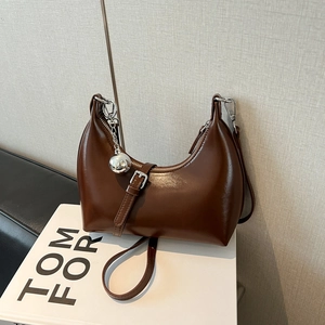 Détail du sac en cuir brillant marron foncé avec breloque sphère argentée et boucle