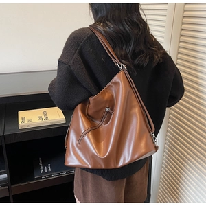 Detail of a large brown soft leather hobo bag with a functional back zipper pocket