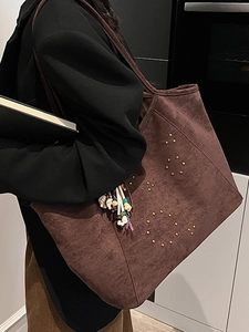 Large brown suede tote bag with metal studs and boho charm carried by model