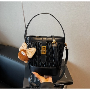 Dettaglio borsa a secchiello plissettata nera con chiusura oro e charm a fiocco