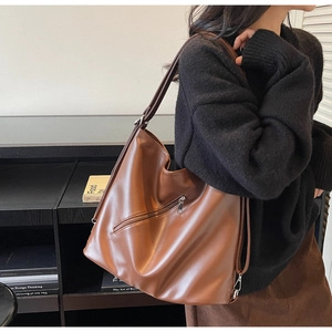 Detailed view of brown leather tote bag with silver zipper and large capacity for commuting