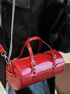 Glossy red bowling style handbag with silver hardware shown on a fashion model