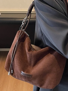 Brown suede tote bag with metal chain strap and minimalist logo detail on a model