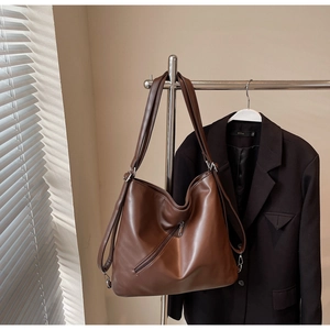 Detail view of large brown vintage tote bag hanging with front zipper pocket and strap