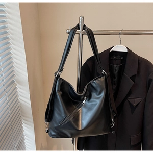 Detail view of black leather tote bag with silver hardware on a professional metal hanger
