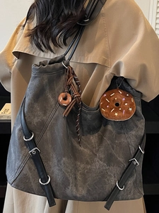 Retro charcoal tote bag with leather strap and donut charm on beige coat model