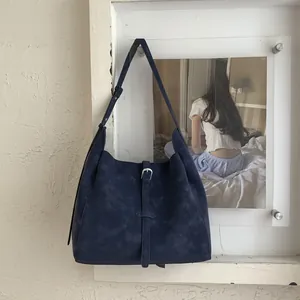 Close-up of matte dark blue large tote bag featuring a prominent silver metal buckle