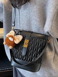 Elegante borsa a secchiello nera a pieghe con chiusura dorata e ciondolo di peluche