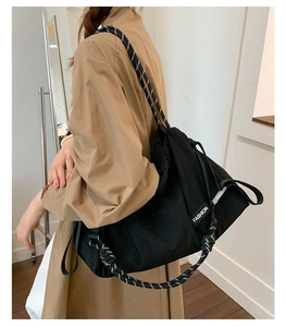 Détail de la bandoulière en toile noire avec sangle en corde tissée et étiquette de mode