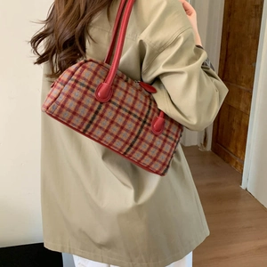 Detail of red and blue plaid tweed shoulder bag with leather straps on a female model