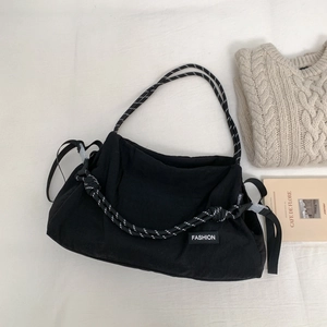 Détail du sac bandoulière en toile noire avec poignée en corde rayée stylée