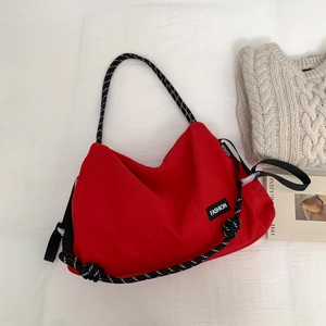 Détail du sac fourre-tout en toile rouge avec corde tressée noire et blanche et étiquette