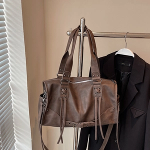 Detailed view of brown retro leather tote featuring cross-lace design and long tassels