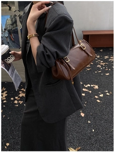 Détail du sac porté épaule marron foncé en cuir brillant avec boucles dorées style urbain