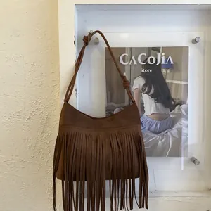 Detail shot of vintage dark brown suede crossbody bag with long tassels and knotted strap