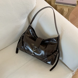 Dettaglio di borsa a spalla in pelle marrone scuro lucida con gancio in metallo argento