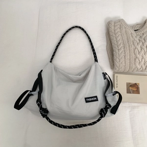 Détail du sac bandoulière gris en nylon avec étiquette fashion et bandoulière tressée