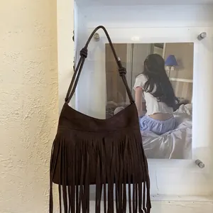 Detailed close-up of dark brown suede crossbody bag with long bohemian tassels