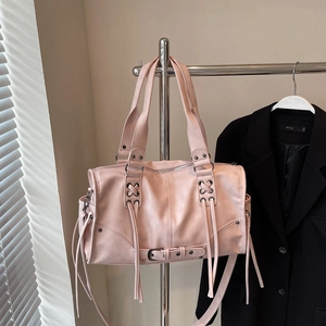 Detailed view of pink Boston bag featuring decorative criss-cross lacing and long tassels